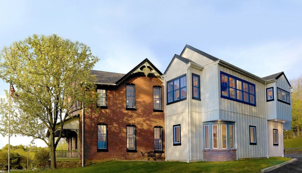 A charming brick and white two-story house with large windows.
